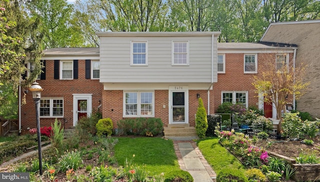 townhome / multi-family property with brick siding and a front lawn