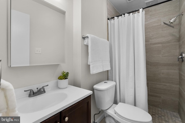 full bath featuring toilet, a tile shower, and vanity
