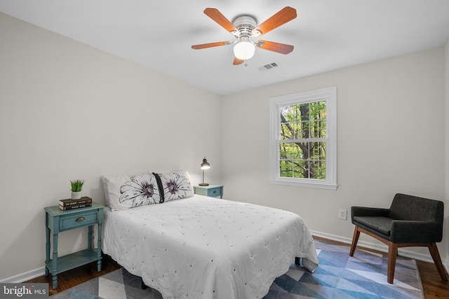 bedroom with visible vents, a ceiling fan, dark wood finished floors, and baseboards