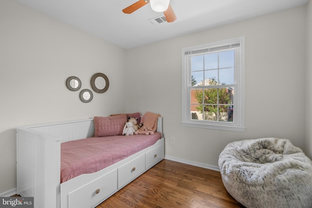 bedroom featuring wood finished floors, visible vents, a ceiling fan, and baseboards