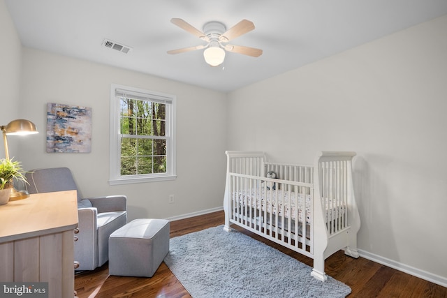 bedroom featuring wood finished floors, visible vents, a nursery area, and baseboards