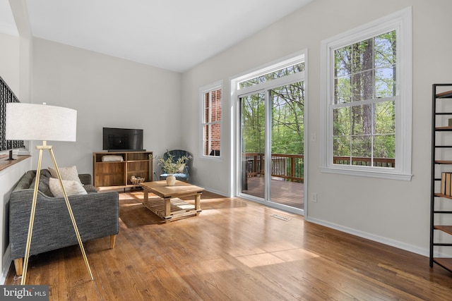 living area featuring wood finished floors, plenty of natural light, visible vents, and baseboards