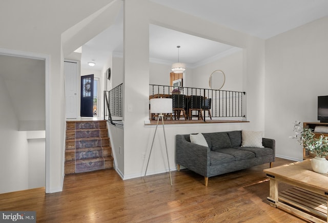 living room with ornamental molding, stairway, wood finished floors, and baseboards
