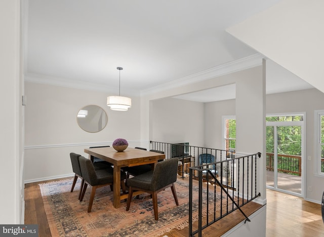 dining space with baseboards, wood finished floors, and crown molding