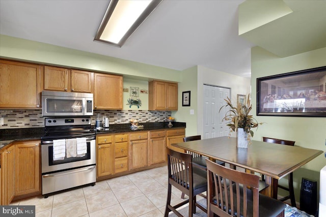 kitchen featuring light tile patterned floors, dark countertops, backsplash, and stainless steel appliances