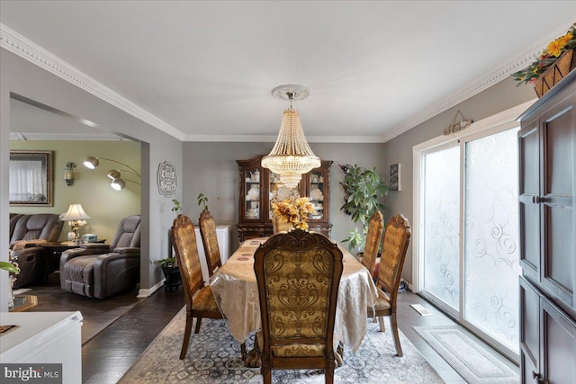 dining room featuring a chandelier, baseboards, ornamental molding, and wood finished floors