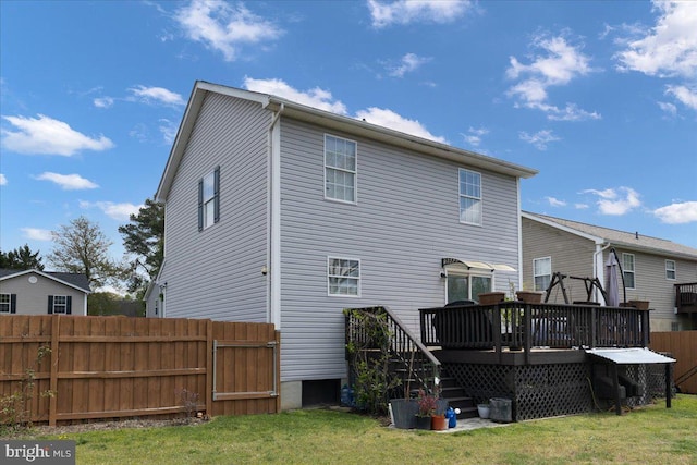 rear view of house with a yard, a deck, and fence
