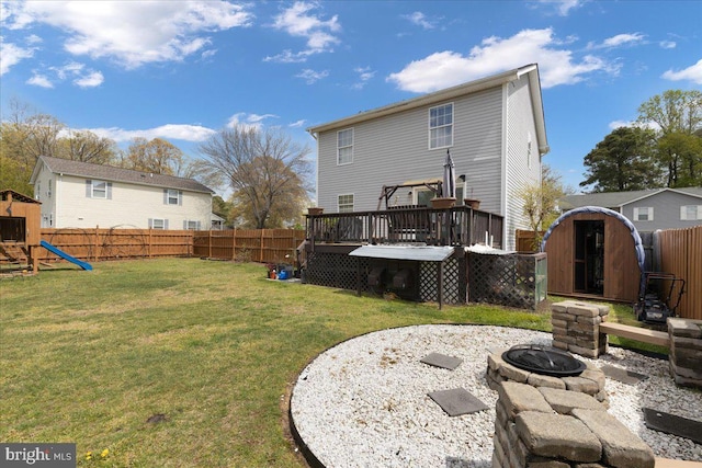 rear view of property featuring a yard, a wooden deck, a fenced backyard, and a playground