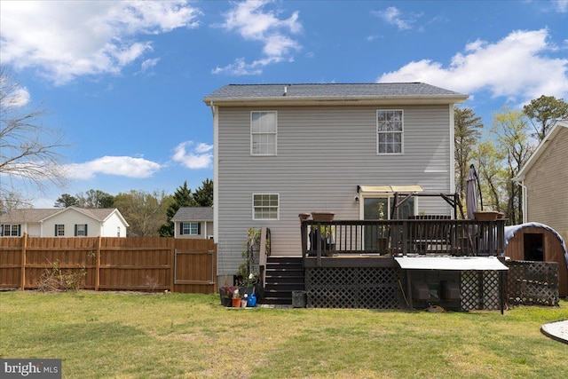 rear view of property with fence, a wooden deck, a lawn, and stairs