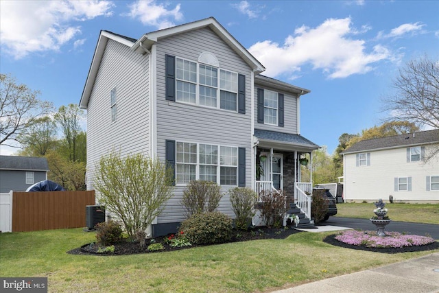 traditional-style house with central AC, fence, and a front lawn