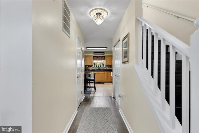 corridor with stairs, light wood finished floors, visible vents, and baseboards