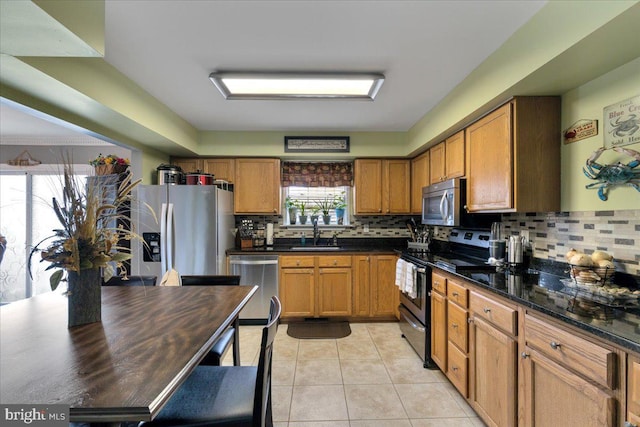 kitchen featuring brown cabinetry, tasteful backsplash, a sink, and appliances with stainless steel finishes