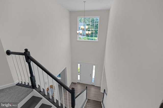 foyer featuring an inviting chandelier, dark wood-type flooring, baseboards, and stairs