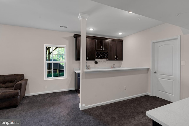 kitchen featuring dark brown cabinetry, visible vents, baseboards, light countertops, and dark colored carpet