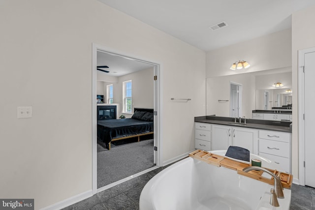 ensuite bathroom featuring vanity, visible vents, a freestanding bath, connected bathroom, and baseboards