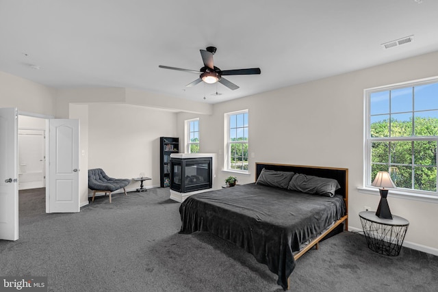 bedroom with carpet flooring, a ceiling fan, a multi sided fireplace, visible vents, and baseboards
