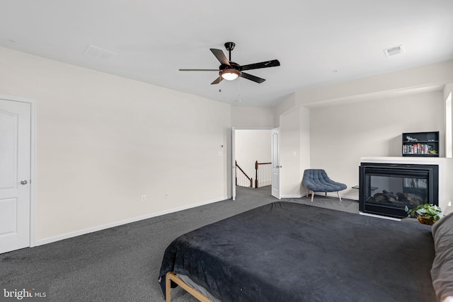 carpeted bedroom featuring ceiling fan, baseboards, a multi sided fireplace, and visible vents