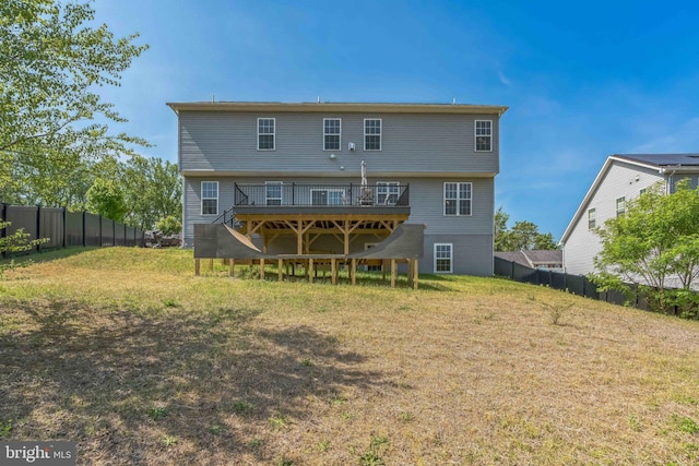 rear view of house with a deck, fence, and a lawn