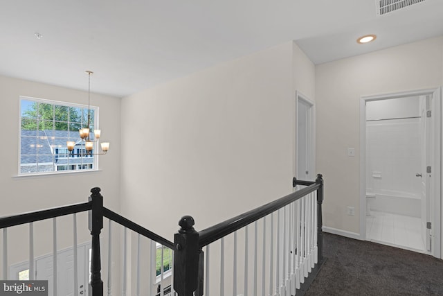 hallway with an upstairs landing, visible vents, recessed lighting, a chandelier, and dark colored carpet