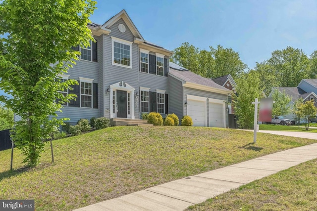 colonial house with an attached garage, concrete driveway, and a front lawn