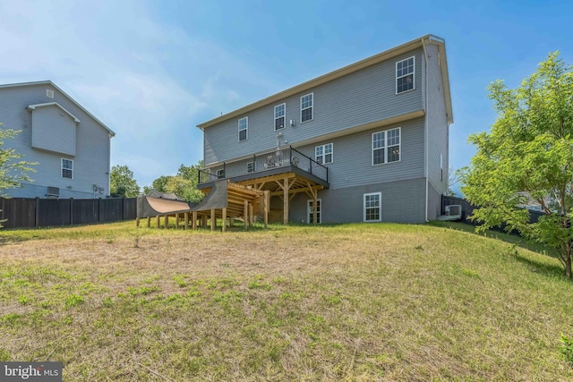 back of property with a yard, a deck, and fence