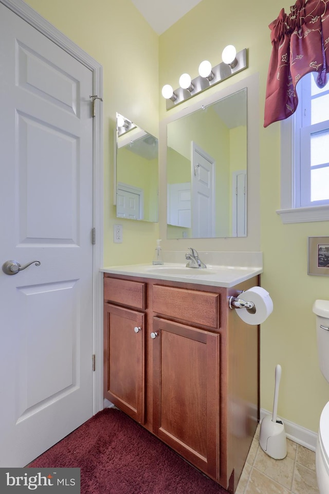 half bathroom with baseboards, toilet, tile patterned flooring, and vanity