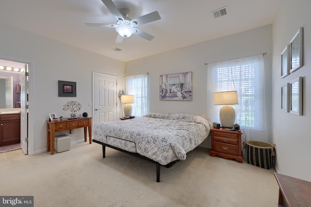 bedroom with light colored carpet, visible vents, connected bathroom, and a ceiling fan