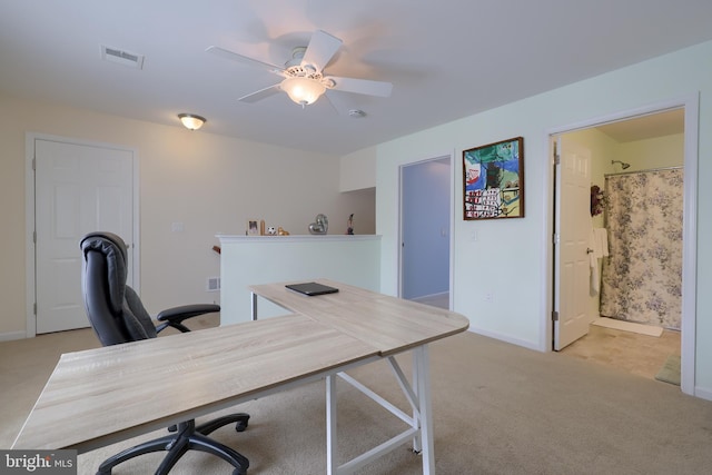 office space featuring light colored carpet, visible vents, ceiling fan, and baseboards