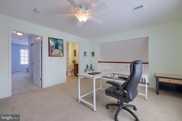 home office with a ceiling fan, visible vents, light carpet, and baseboards