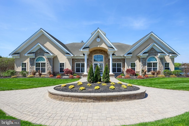 view of front of property with a front lawn, stone siding, and stucco siding