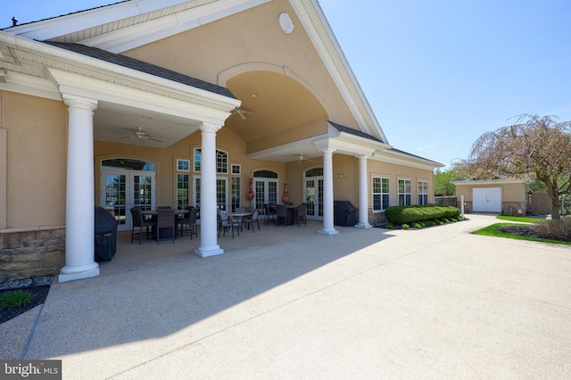 view of patio / terrace featuring a storage unit, an outbuilding, french doors, outdoor dining space, and a ceiling fan