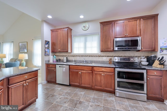 kitchen featuring recessed lighting, decorative backsplash, appliances with stainless steel finishes, stone counters, and a sink