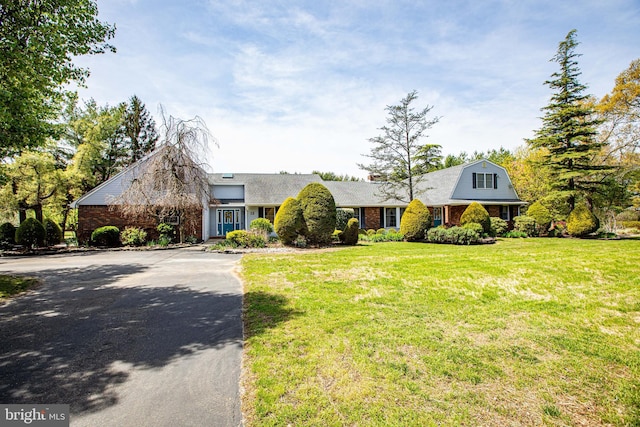 view of front of house featuring a front yard, brick siding, and aphalt driveway