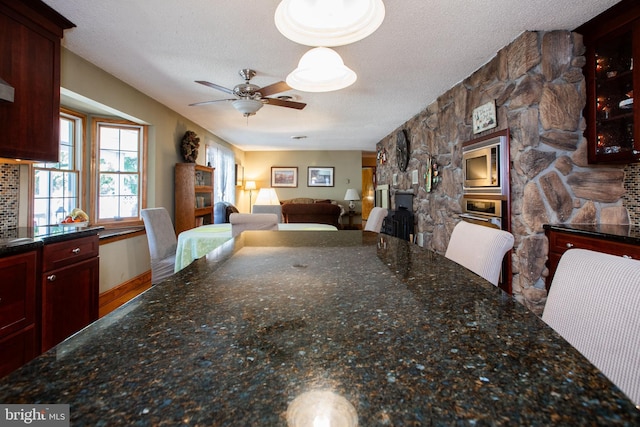 dining area featuring ceiling fan, a fireplace, and a textured ceiling