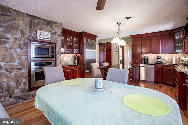 dining room with a textured ceiling, wood finished floors, and visible vents