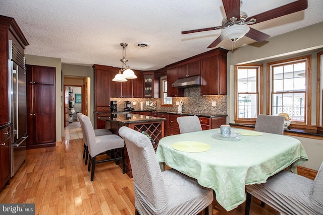 dining room with plenty of natural light, a ceiling fan, light wood finished floors, and visible vents