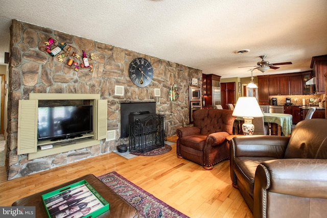 living area with a ceiling fan, a textured ceiling, and light wood-style flooring