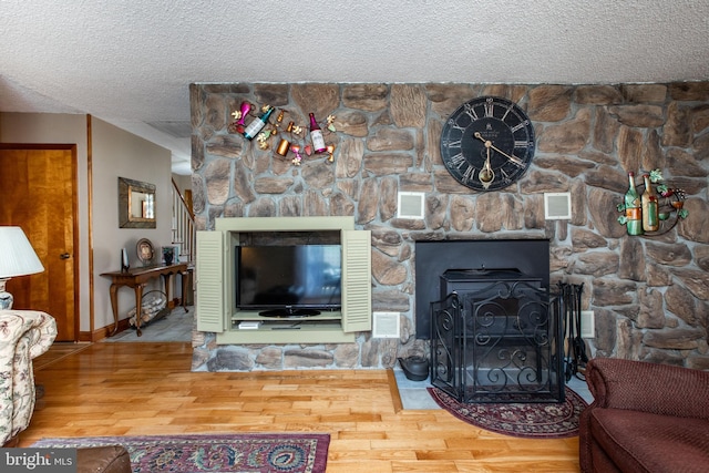 living room with stairs, a textured ceiling, wood finished floors, and visible vents