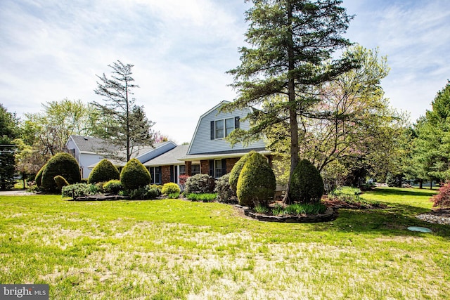 view of front of home with brick siding, a front yard, and a gambrel roof