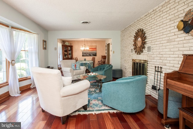 living area featuring an inviting chandelier, wood finished floors, brick wall, and visible vents