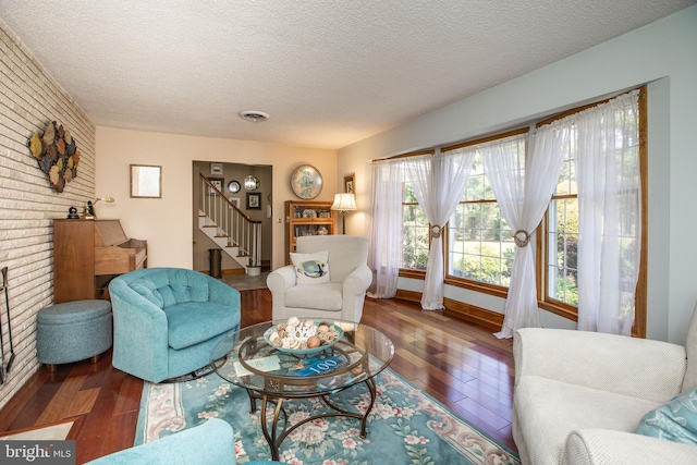 living area with visible vents, a textured ceiling, hardwood / wood-style floors, and stairway
