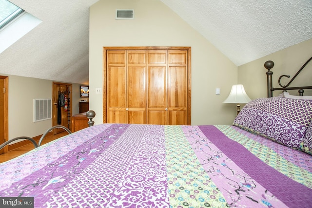 bedroom with vaulted ceiling with skylight, a closet, a textured ceiling, and visible vents