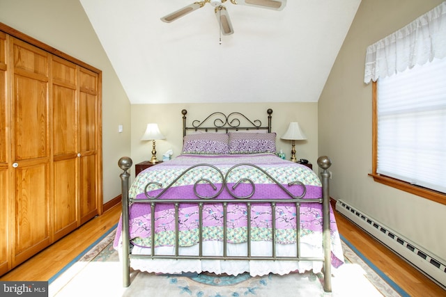 bedroom with a ceiling fan, a baseboard heating unit, vaulted ceiling, and light wood-type flooring
