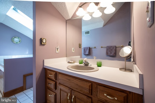 bathroom featuring visible vents, tile patterned flooring, vanity, lofted ceiling with skylight, and a notable chandelier