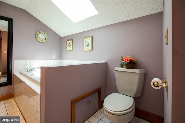 bathroom featuring a garden tub, toilet, baseboards, tile patterned floors, and vaulted ceiling with skylight