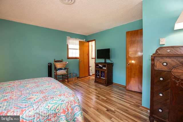 bedroom with a textured ceiling and wood finished floors
