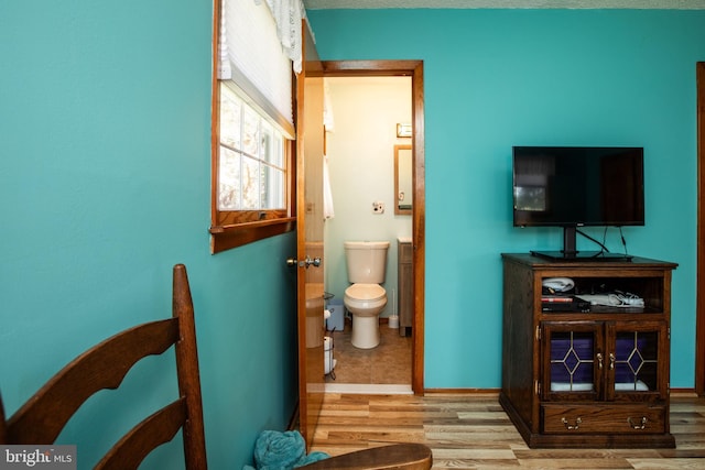 bathroom with baseboards, toilet, and wood finished floors