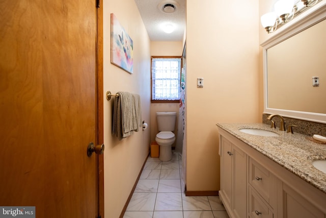 full bathroom with double vanity, marble finish floor, toilet, a textured ceiling, and a sink