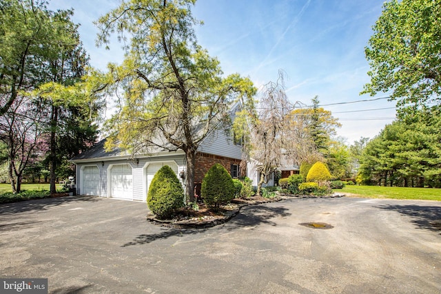 view of home's exterior featuring brick siding, aphalt driveway, and a garage