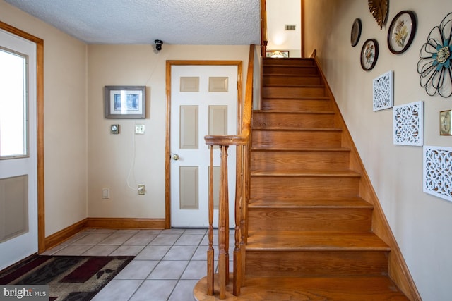 stairs featuring tile patterned floors, a textured ceiling, and visible vents